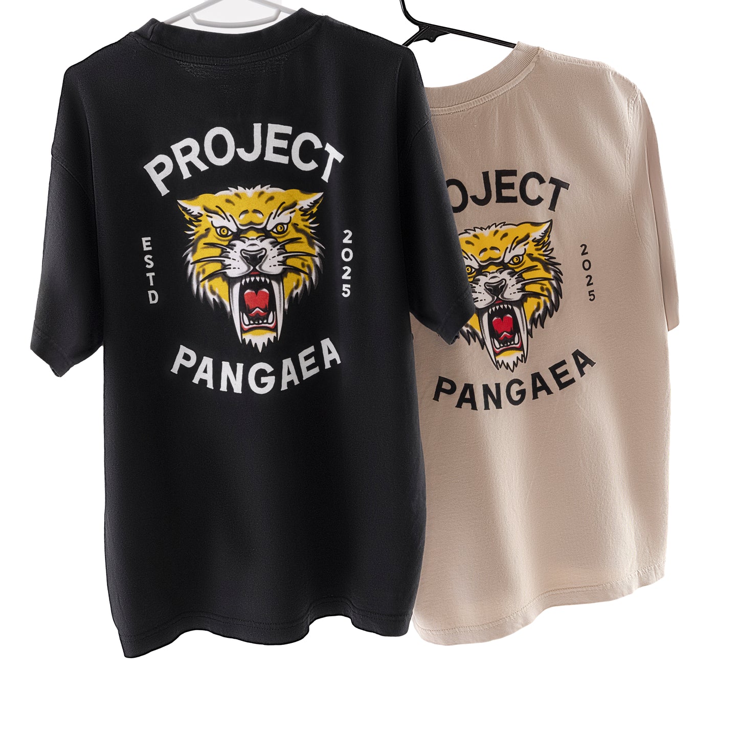 Tan and Black Black 100% cotton shirts on hangers - Sabertooth Tiger face with "est 2025" on sides and "Project Pangaea" written above and below. 

heavy weight, high quality stylish sabertooth t-shirt. 
Smilodon t shirt, ice age t-shirt 
prehistoric t-shirt